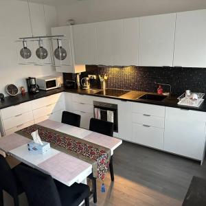 A home away from home في رين: مطبخ مع دواليب بيضاء وطاولة مع كراسي