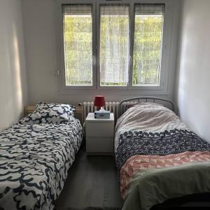 A home away from home في رين: غرفة نوم بسريرين وطاولة بها مصباح