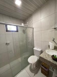 a bathroom with a toilet and a shower and a sink at Pousada Kaluanã in Japaratinga
