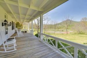 un porche de una casa con sillas blancas. en Historic Countryside Escape - Relax, Hike, & Fish!, en Goshen