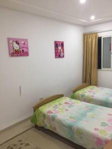- une chambre avec 2 lits et 2 photos sur le mur dans l'établissement Résidence le corail de chat meriem, à Sousse