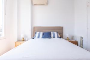 1 dormitorio con 1 cama blanca grande con almohadas azules en Alcalá Street View, en Madrid