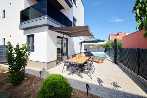 a patio with a table and chairs and an umbrella at ZEN apartment - private pool in Trogir