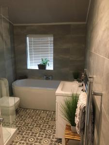 a bathroom with a tub and a toilet and a sink at The Terrace Hoole, cosy modern 2 bedroom house in Chester