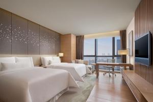 um quarto de hotel com duas camas e uma televisão de ecrã plano em The Westin Chongqing Liberation Square em Chongqing