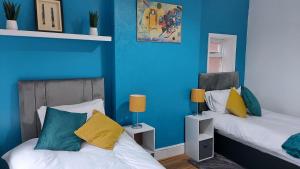 two beds in a room with blue walls at HILLTOP PLACE SUITES near MEADOWHALL in Sheffield