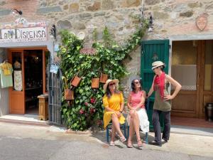 Tre donne sedute su una sedia di fronte a un edificio di Casa Al Chianti B&B a Greve in Chianti