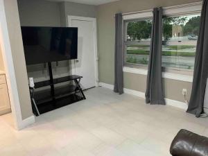 a living room with a flat screen tv and two windows at Apartment in Daytona Beach 1BR 1Bath Centrally Located in Daytona Beach