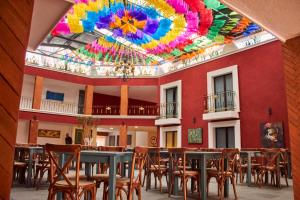 Habitación con mesas, sillas y techo colorido. en Hotel Casa Real Cholula, en Cholula