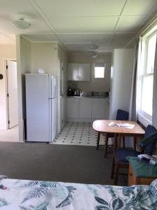 a kitchen with a white refrigerator and a table at Tui Cottage in Te Arai