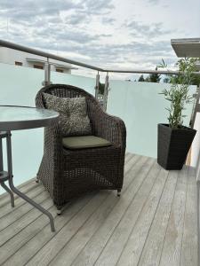 una silla de mimbre y una mesa en el balcón en Apartament 28 w Dolinie Baryczy - 5D Apartamenty, en Milicz