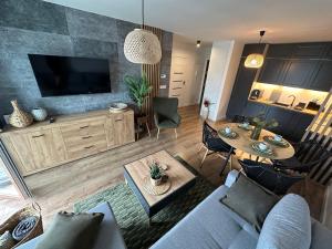 een woonkamer met een bank en een tv bij Apartament 28 w Dolinie Baryczy - 5D Apartamenty in Milicz