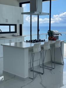 a kitchen with white counters and white counter stools at Villa Ocean Blue in Las Terrenas