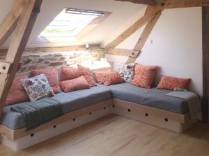 - un canapé avec des oreillers dans le grenier dans l'établissement Gite Fleurs d'Esse, à Saint-Paul-la-Roche