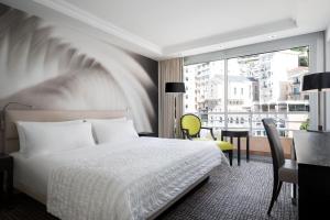 a hotel room with a bed and a desk and a window at Le Méridien Beach Plaza in Monte Carlo