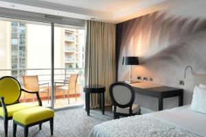 a hotel room with a bed and a desk and chairs at Le Méridien Beach Plaza in Monte Carlo