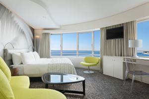 a hotel room with a bed and a desk and chairs at Le Méridien Beach Plaza in Monte Carlo