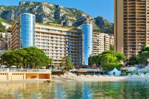 uma vista para uma praia com edifícios e uma montanha em Le Méridien Beach Plaza em Monte Carlo