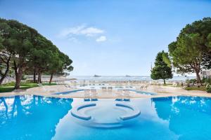a pool with blue water and chairs and trees at Le Méridien Beach Plaza in Monte Carlo