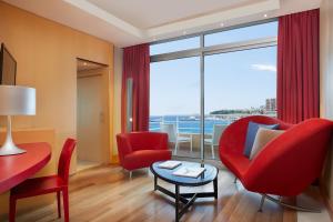 a living room with red chairs and a table at Le Méridien Beach Plaza in Monte Carlo