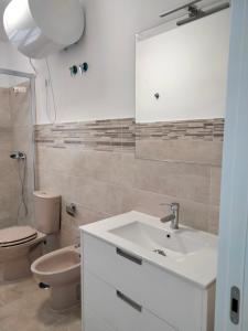 een badkamer met een wastafel, een toilet en een spiegel bij Apartamentos Playa Holidays in Málaga