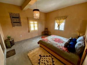 a bedroom with a bed and a rug and windows at Les chandelles in Tinerhir