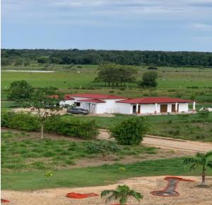 een wit gebouw met een rood dak in een veld bij Mi finca en el llano in La Floresta