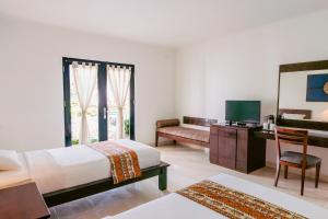 a bedroom with a bed and a desk and a television at Legong Keraton Beach Hotel in Canggu