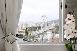 a window with a view of a river and a bridge at Magnífico "QUARTO" Privativo em Apto, com Vista Espetacular in Florianópolis