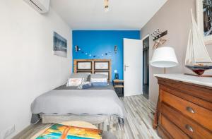 a bedroom with a bed and a blue wall at Maison de vacances à l'Ayguade classée 3 étoiles, climatisée,3mn à pied plage et restos ,5mn aéroport, 10mn gare in Hyères