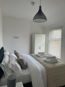 um quarto branco com uma cama grande e almofadas em New Sandpiper Apartments em Fleetwood