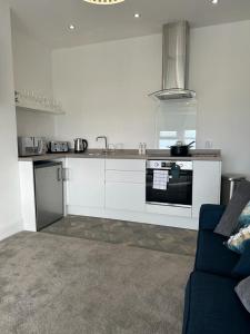 uma cozinha branca com um fogão e um sofá em New Sandpiper Apartments em Fleetwood