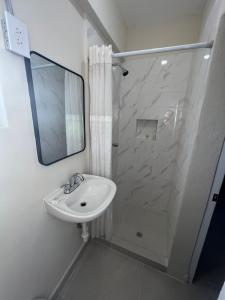 a bathroom with a sink and a shower with a mirror at HOTEL VILLAGRAN in Tijuana