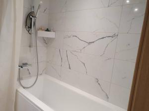a white bathroom with a tub and a marble wall at Bright 3-room apartment in Mustamäe in Tallinn
