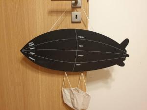 a black surfboard hanging on a wall with a bag at Bright 3-room apartment in Mustamäe in Tallinn