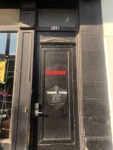 Eine schwarze Tür mit einem Schild drauf. in der Unterkunft Pensione Popolo in Montreal