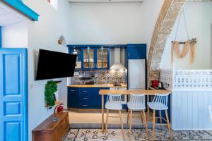 une cuisine avec des armoires bleues et une table et des tabourets en bois dans l'établissement SUN PETRADI Tradition & Luxury, à Koskinou