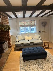 a living room with a couch and a blue ottoman at Historic Cambridgeshire Cottage in Godmanchester