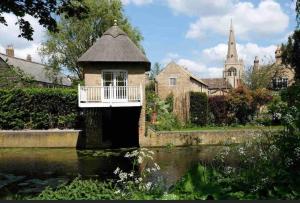 ein kleines Gebäude mit einer Brücke über ein Gewässer in der Unterkunft Historic Cambridgeshire Cottage in Godmanchester