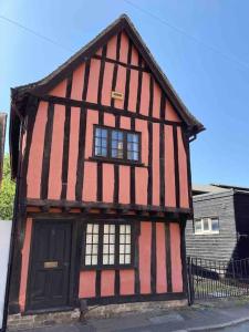 ein rot-schwarzes Gebäude mit einer Tür und Fenstern in der Unterkunft Historic Cambridgeshire Cottage in Godmanchester