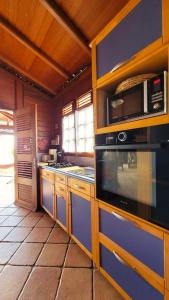 a kitchen with a stove and a microwave at VILLA TI'ROUCOU 3 étoiles - vue mer et piscine privée sans vis à vis in Bouillante +16 photos