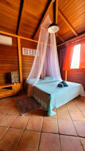 Schlafzimmer mit einem Bett mit Moskitonetz in der Unterkunft VILLA TI'ROUCOU 3 étoiles - vue mer et piscine privée sans vis à vis in Bouillante