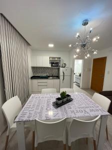 uma mesa de jantar branca com cadeiras brancas e uma cozinha em Carlos Paz-Lake Towers em Villa Carlos Paz