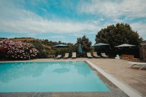 a blue swimming pool with chairs and umbrellas at Villa Alba Sul Mare in Budoni