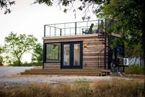a small house with a balcony on top of it at New Wilderness Hideout-Cozy Container Home in Fredericksburg