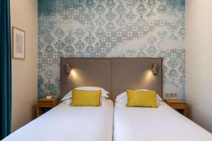 een slaapkamer met 2 bedden en gele kussens bij Best Western Plus Monopole Métropole in Straatsburg