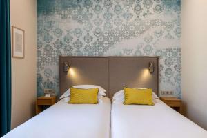 a bedroom with two beds with yellow pillows at Best Western Plus Monopole M&eacute;tropole in Strasbourg