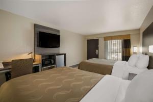a hotel room with two beds and a flat screen tv at Quality Inn Commerce in Commerce