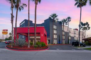 un bâtiment avec des palmiers en face d'un parking dans l'établissement Best Western Plus Commerce Hotel, à Los Angeles