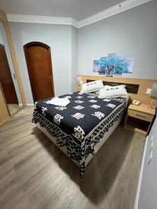 um quarto com uma cama com um cobertor preto e branco em FLAT no Gonzaga com estacionamento incluso em Santos